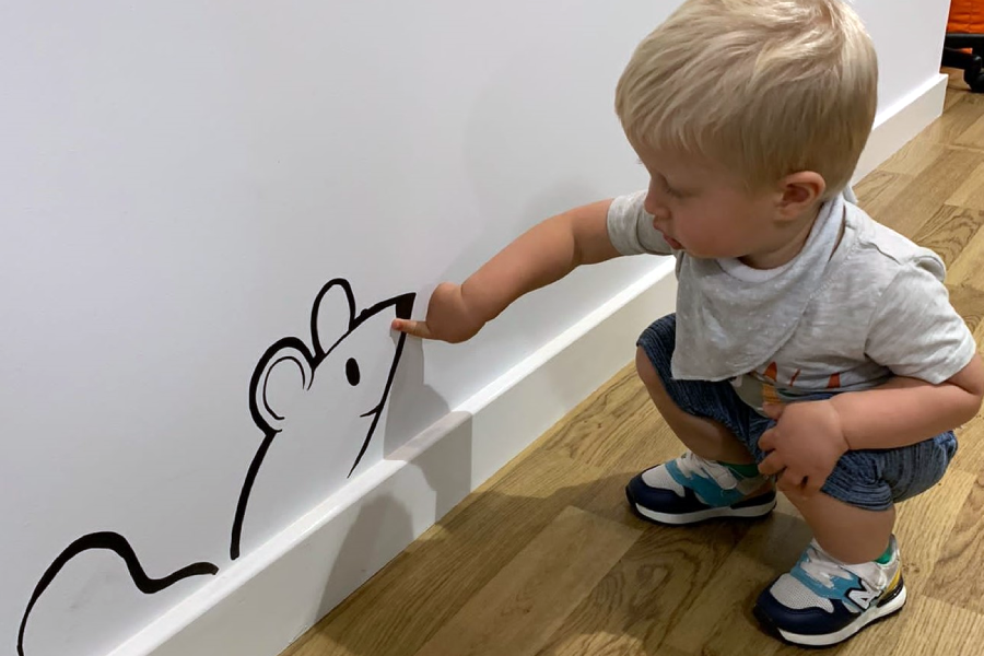 Young child looking at mouse mural on wall